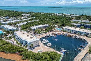 An aerial view of a coastal resort with multiple buildings, a marina, and a clear view of the ocean. - Mariner’s Club, Key Largo Home!!! 4bedroom 4bathroom Tropical Oasis (Key Largo)