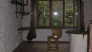 Ein rustikaler Raum mit freiliegenden Holzbalken, einem großen Fenster mit Blick auf Bäume, einem Holzschemel und einer Barzeile.