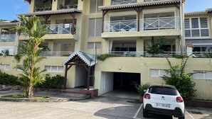 A multi-story hotel with balconies, a covered entrance, and a parking area.