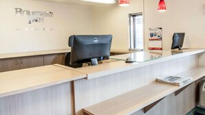 A reception desk with a Dell computer, a glass top, and a red pendant light. - Rodeway Inn Albuquerque West (Albuquerque)