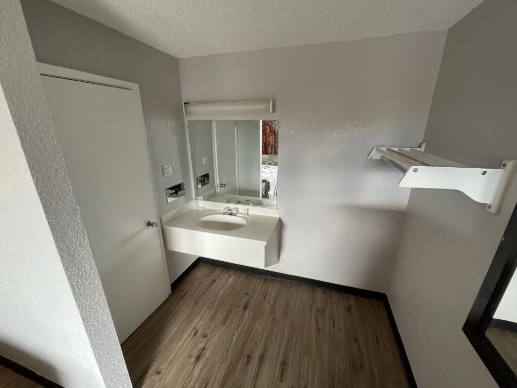 Une petite salle de bain moderne avec un lavabo blanc, un miroir et un plancher en bois.