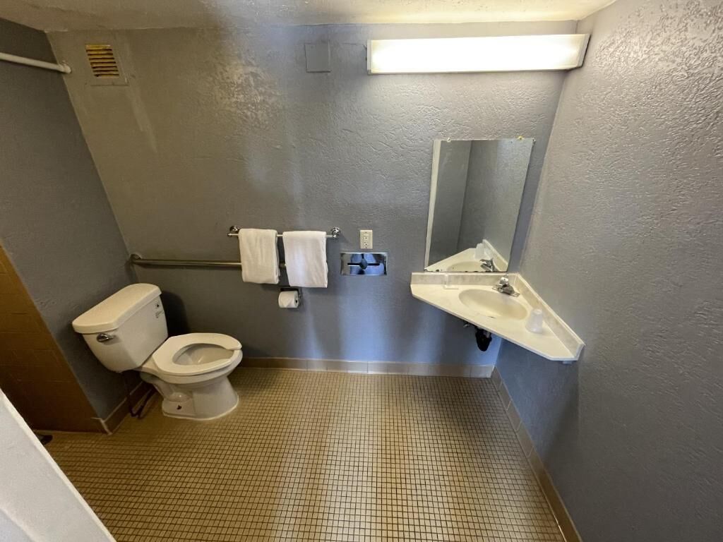 A small bathroom with a toilet, sink, and mirror.