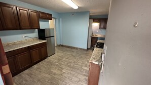 A kitchen with wooden cabinets, a stainless steel refrigerator, and a granite countertop. - Rodeway Inn Albuquerque West (Albuquerque)