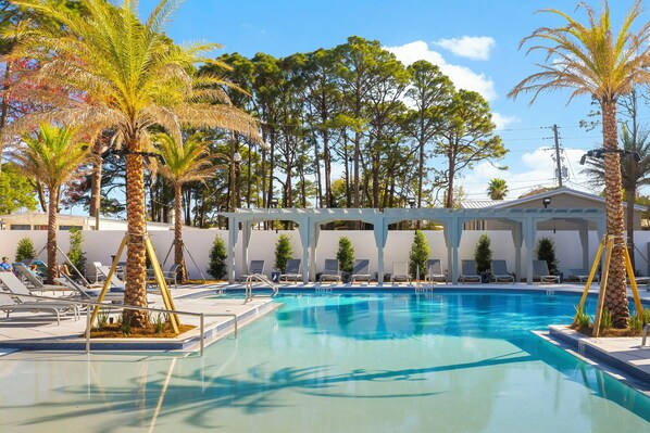 A swimming pool with lounge chairs and palm trees.