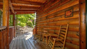 A wooden cabin with a porch, rocking chairs, and a framed leaf decoration. - Luxury cabin with private outdoor hot tub and access to resort pool (Sevierville)