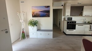 Une cuisine moderne avec vue sur la mer, des meubles blancs et une plante.