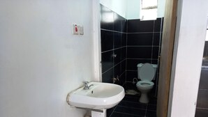 Une salle de bain avec un lavabo blanc, des toilettes et des murs recouverts de carreaux noirs.