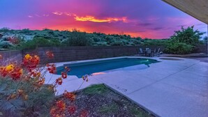 Una piscina con zona de terraza, rodeada por un jardín ajardinado con diversas plantas y arbustos.