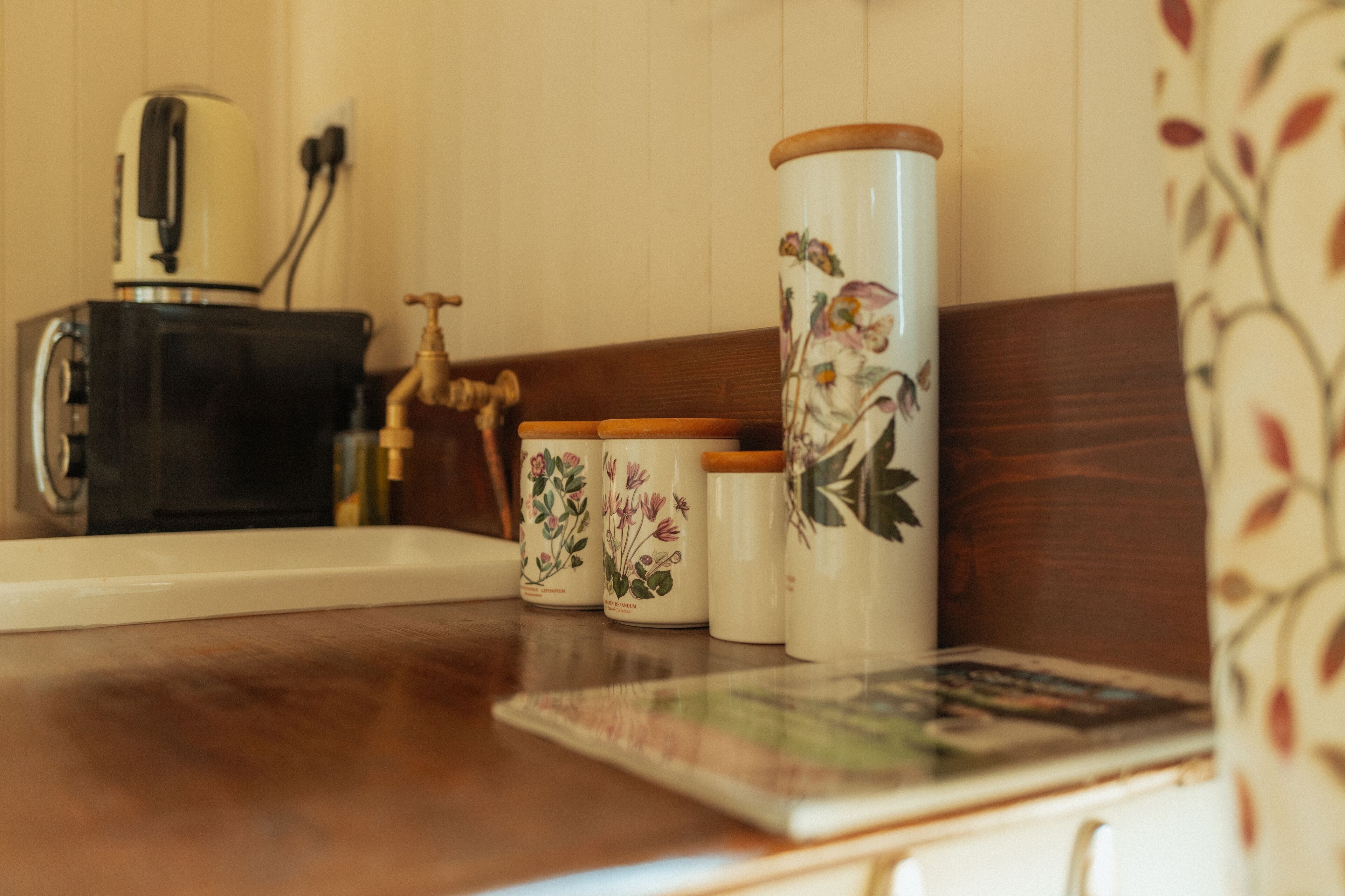 Eine Küchenarbeitsplatte mit Kaffeemaschine, Wasserkocher und drei Keramikbehältern mit Deckeln.