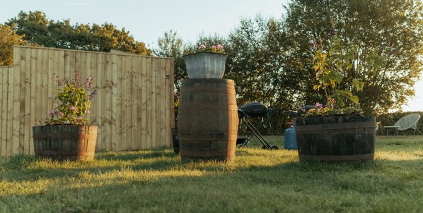 A garden with three large planters and a wooden fence. - Glamping in Wiltshire in our Luxury Shepherds Hut (Chippenham)