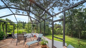 A covered patio with outdoor furniture, a table, and potted plants. - ‘Our Encanto’ -quiet golf course view-Tampa suburb (Valrico)