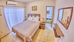 Un dormitorio con cama, mesita de noche y espejo.