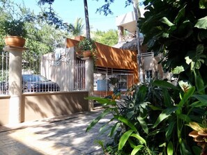 A gated residential area with a paved walkway, a parked car, and lush greenery. - Perla 61: Groundfloor 2BR w Pool - 6 blocks to Beach (Bucerías)