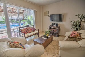 A living room with a sofa, a coffee table, a TV, and a plant. - Perla 61: Groundfloor 2BR w Pool - 6 blocks to Beach (Bucerías)