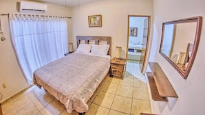 A bedroom with a bed, bedside table, and a mirror.