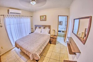 A bedroom with a bed, bedside table, and a mirror.
