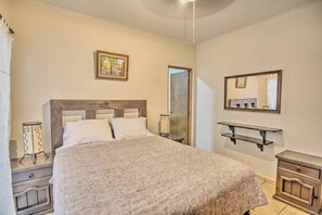 A bedroom with a large bed, a bedside table, a nightstand, a mirror, and a shelf. - Perla 61: Groundfloor 2BR w Pool - 6 blocks to Beach (Bucerías)