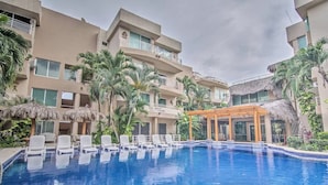 A hotel with a swimming pool surrounded by palm trees and lounge chairs.