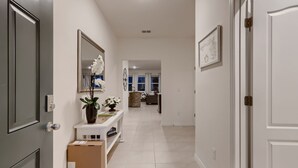 Un pasillo con una puerta blanca, un console con un florero y un espejo en la pared. Hay dos cajas de cartón en el suelo.