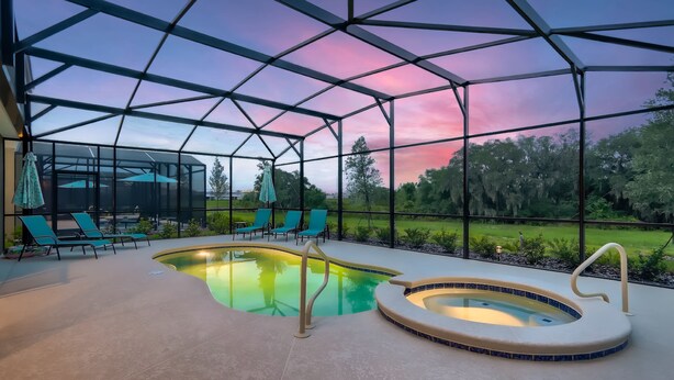 Zona de piscina con cerramiento de vidrio, sillas de descanso y jacuzzi.