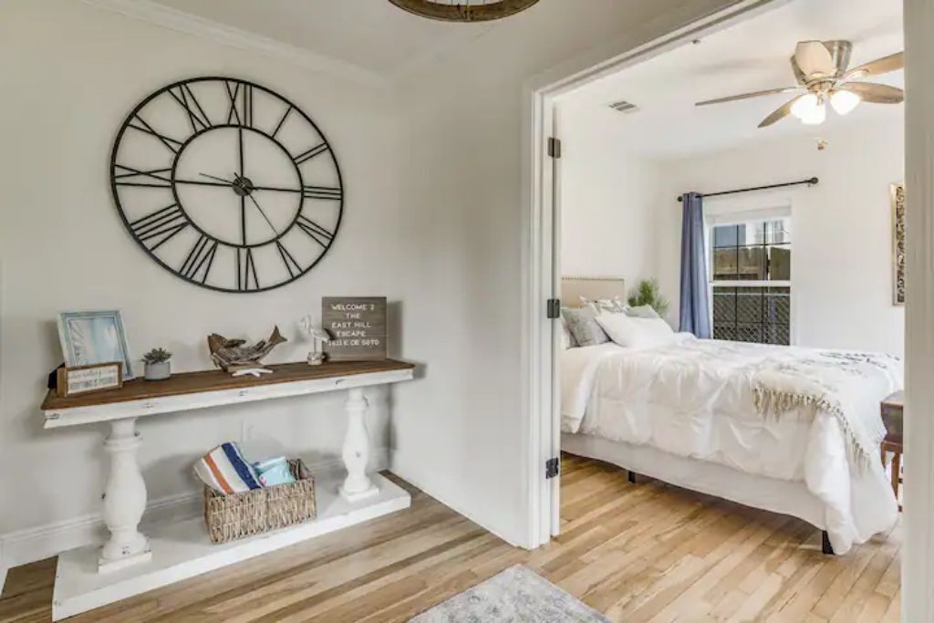 Un dormitorio con cama, un reloj de pared grande, una consola y un cartel que dice "WELCOME TO THE EAST HILL ESCAPE".