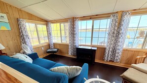 A cozy cabin-style room with a large window, a fireplace, a blue sofa, and a wooden bench. - Lakefront Cabin w/ Dock & Kayaks, Perfect Summer Stay
Rustic Nautic - Cabin 9 (South Haven)