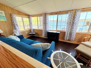 Una habitación acogedora estilo cabaña con un ventanal grande, chimenea, sofá azul y banco de madera.