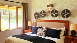 Un dormitorio con una cama, mesitas de noche, un ventilador de techo y una ventana con cortinas.
