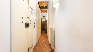 Un pasillo estrecho con piso de cuadros, paredes blancas y un radiador a la derecha.
