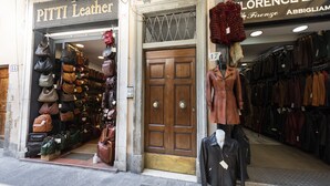 Una tienda con una variedad de bolsos y un maniquí vestido con abrigo.