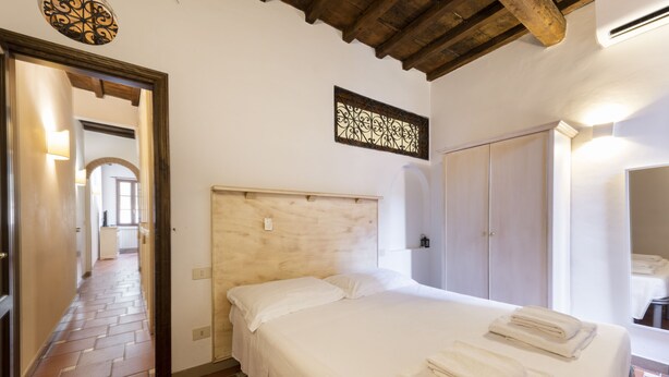 Un dormitorio con cabecera de madera, una cama con ropa blanca y un juego de toallas sobre la cama.