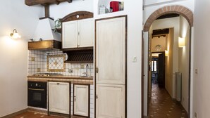 Una cocina con armarios blancos, salpicadero y piso de azulejos.