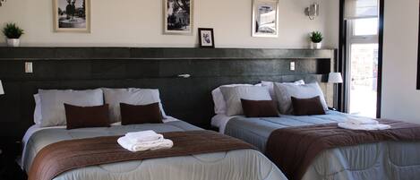A hotel room with two beds, a dark headboard, and framed pictures on the wall.