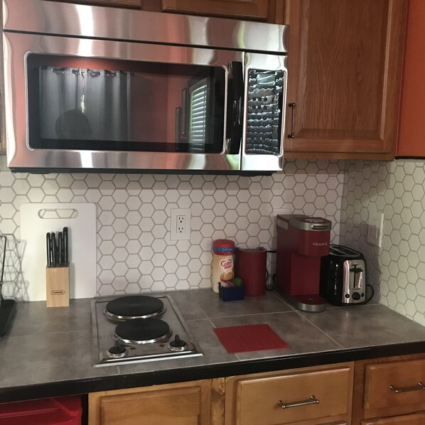 A kitchen with a stainless steel microwave, a coffee maker, and a toaster on the countertop.