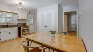 Cozinha com armários brancos, uma mesa de madeira e um candelabro.