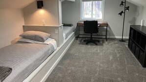 Quarto compacto com beliche, escrivaninha, cadeira e luminária de pé.