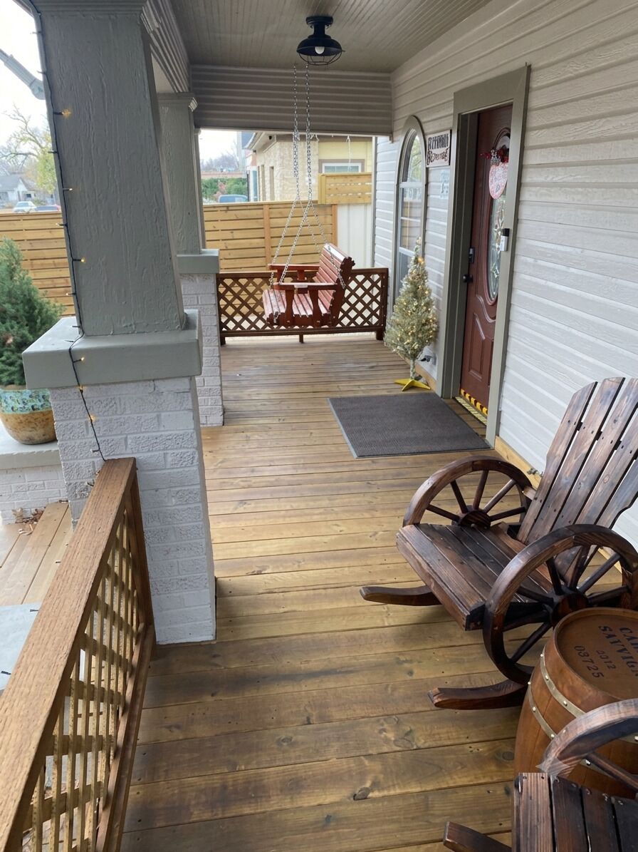 A covered porch with a wooden floor, a swing chair, a wooden bench, and a barrel.