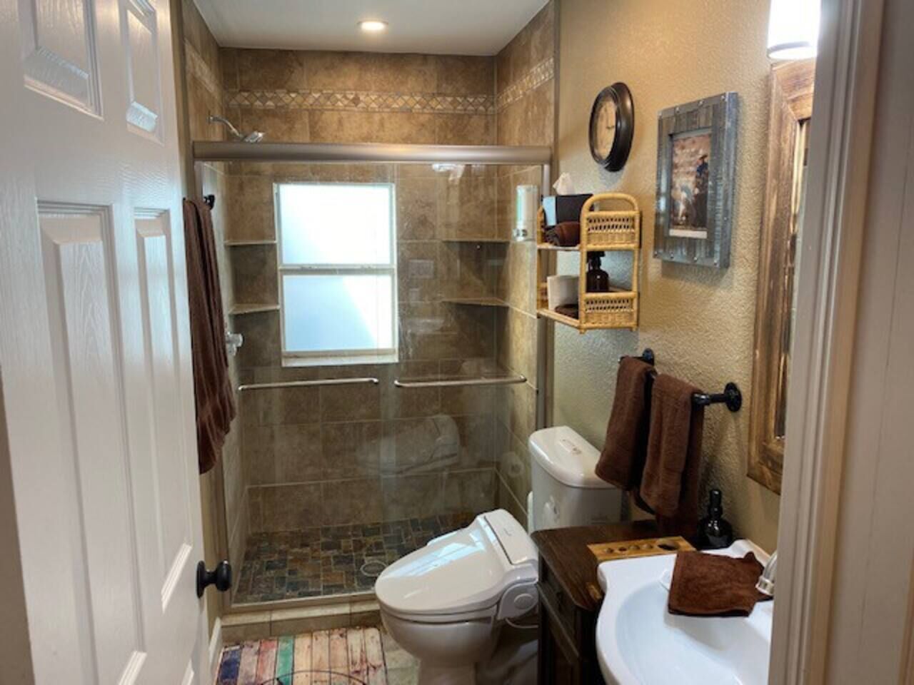 A bathroom with a glass-enclosed shower, a toilet, and a sink.