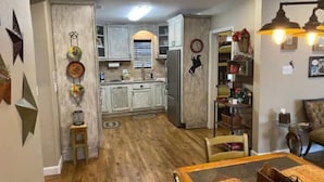 Ein geräumiger Wohnbereich mit Holzboden, einem Esstisch und einer Küche im Hintergrund.