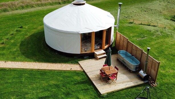 Une yourte dotée d’une terrasse en bois, d’un bain à remous et d’un sauna.