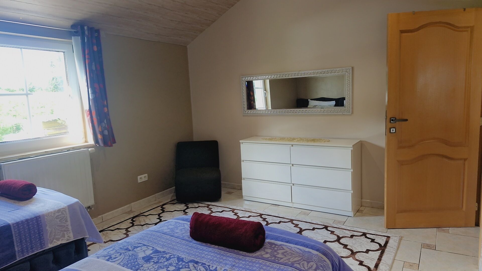 Una camera da letto con un letto, una cassettiera, uno specchio e una porta.