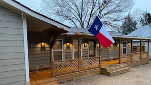 Un edificio con porche y la bandera de Texas.