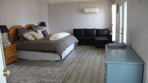 Une chambre à coucher comprenant un lit, un canapé, une commode, un ventilateur de plafond et un appareil de climatisation.