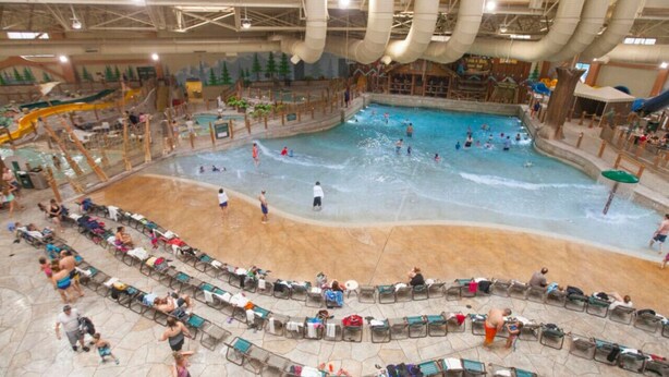 Un parc aquatique intérieur doté de plusieurs piscines, de toboggans et d’un espace détente avec des chaises.