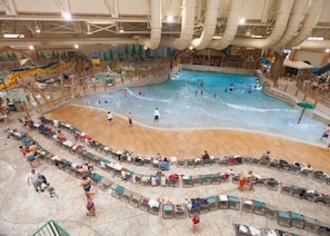 An indoor water park with multiple pools, slides, and a seating area with chairs.