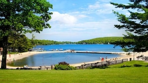 Une plage avec une clôture en bois, une zone herbeuse et un ciel bleu dégagé.