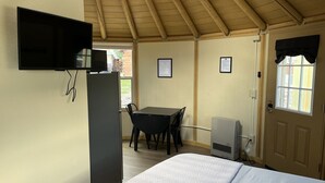 A room with a bed, a desk, a chair, a television mounted on the wall, and a door with a window.