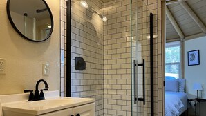 A modern bathroom with a white sink, black faucet, and a glass shower enclosure.