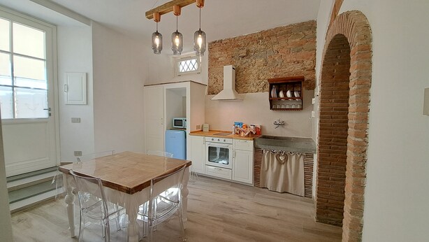 Una cocina con una mesa y sillas de madera, un muro de ladrillo y una lámpara colgante.