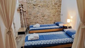 Una habitación con dos camas, una pared de piedra y una alfombra estampada.